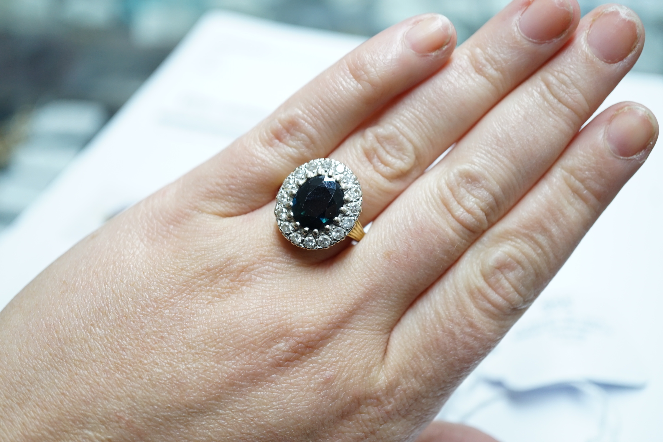 A 1970's? 18ct gold, single stone oval cut sapphire and illusion set diamond cluster ring, size O/P, gross weight 8.2 grams.